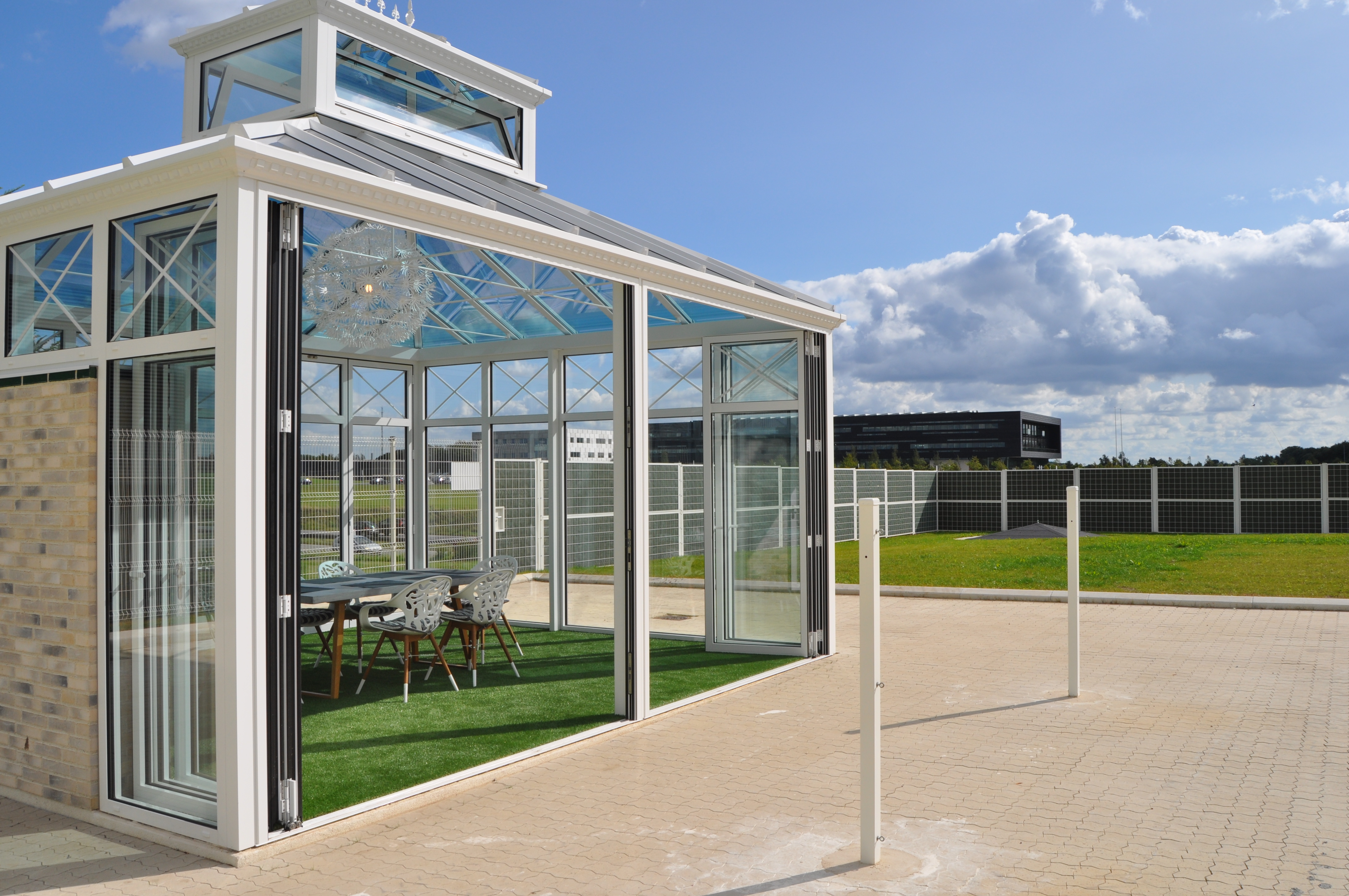 Paviljong med store panoramavinduer i et fellesområde i en bedrift, skjermet med Noistop® Steel støygjerde fra Poda Gjerder