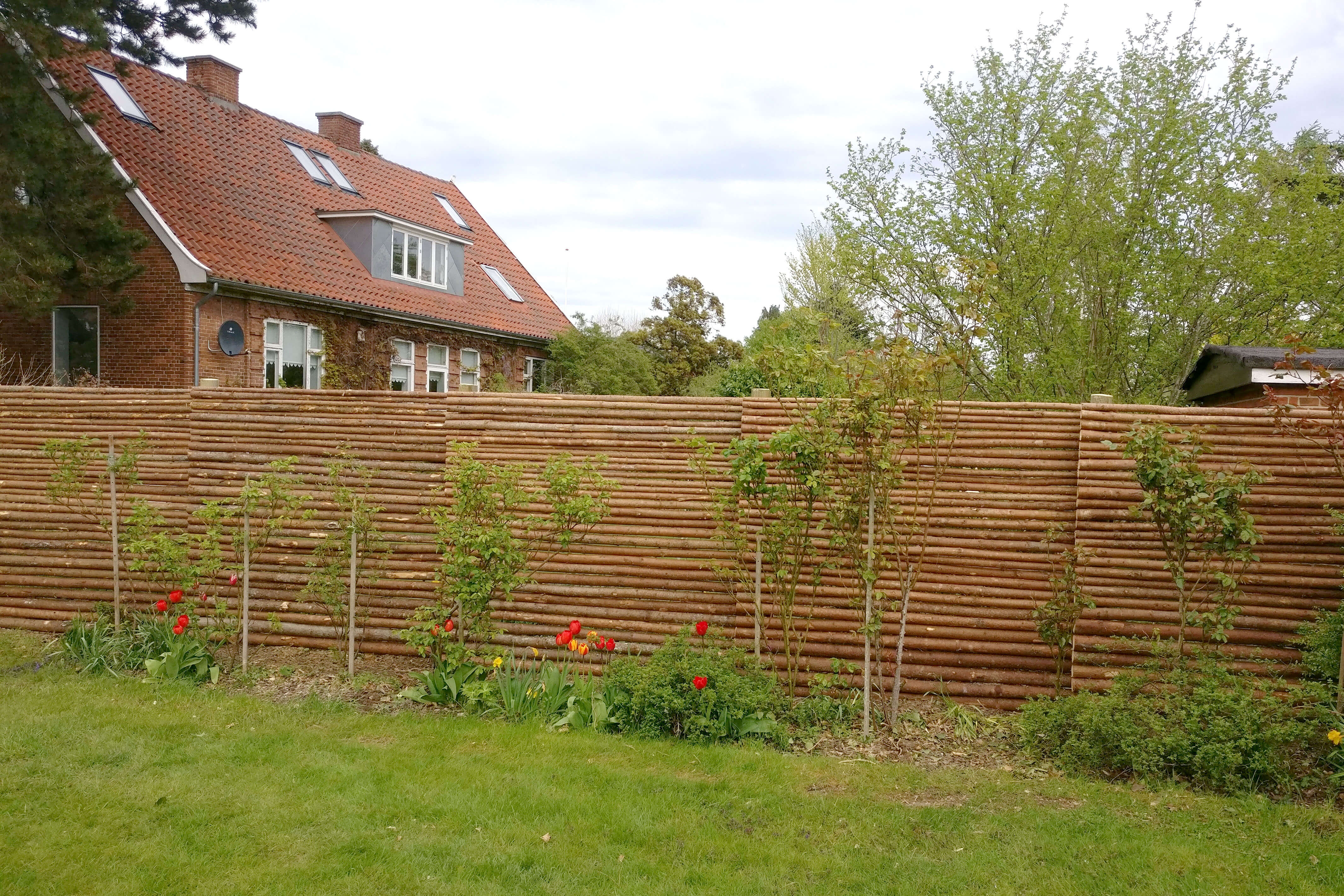 Hagegjerder laget av rafter med bark som brukes som barriere mellom to hager