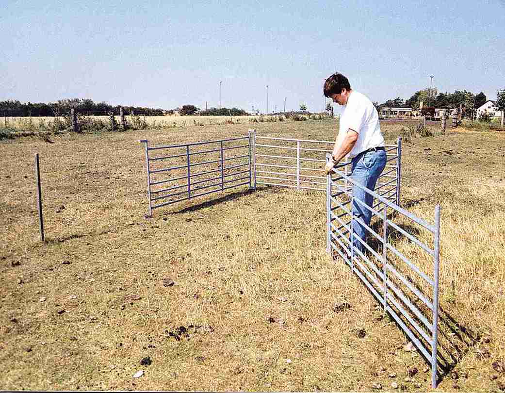 En mann i hvit t-skjorte er i ferd med å sette sammen en fanggrind.