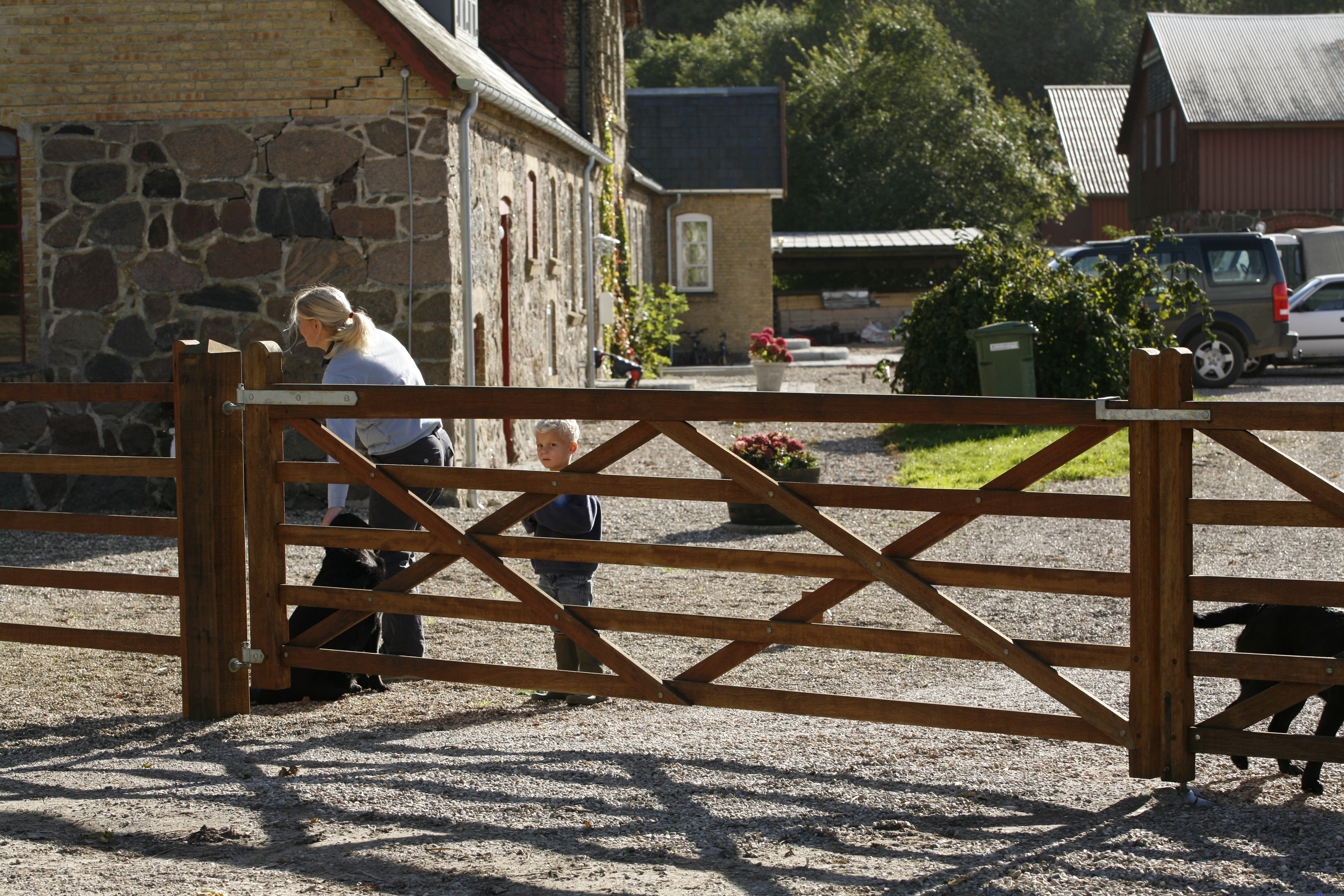 En hund, en kvinne og en gutt står bak en «Country House»-grind