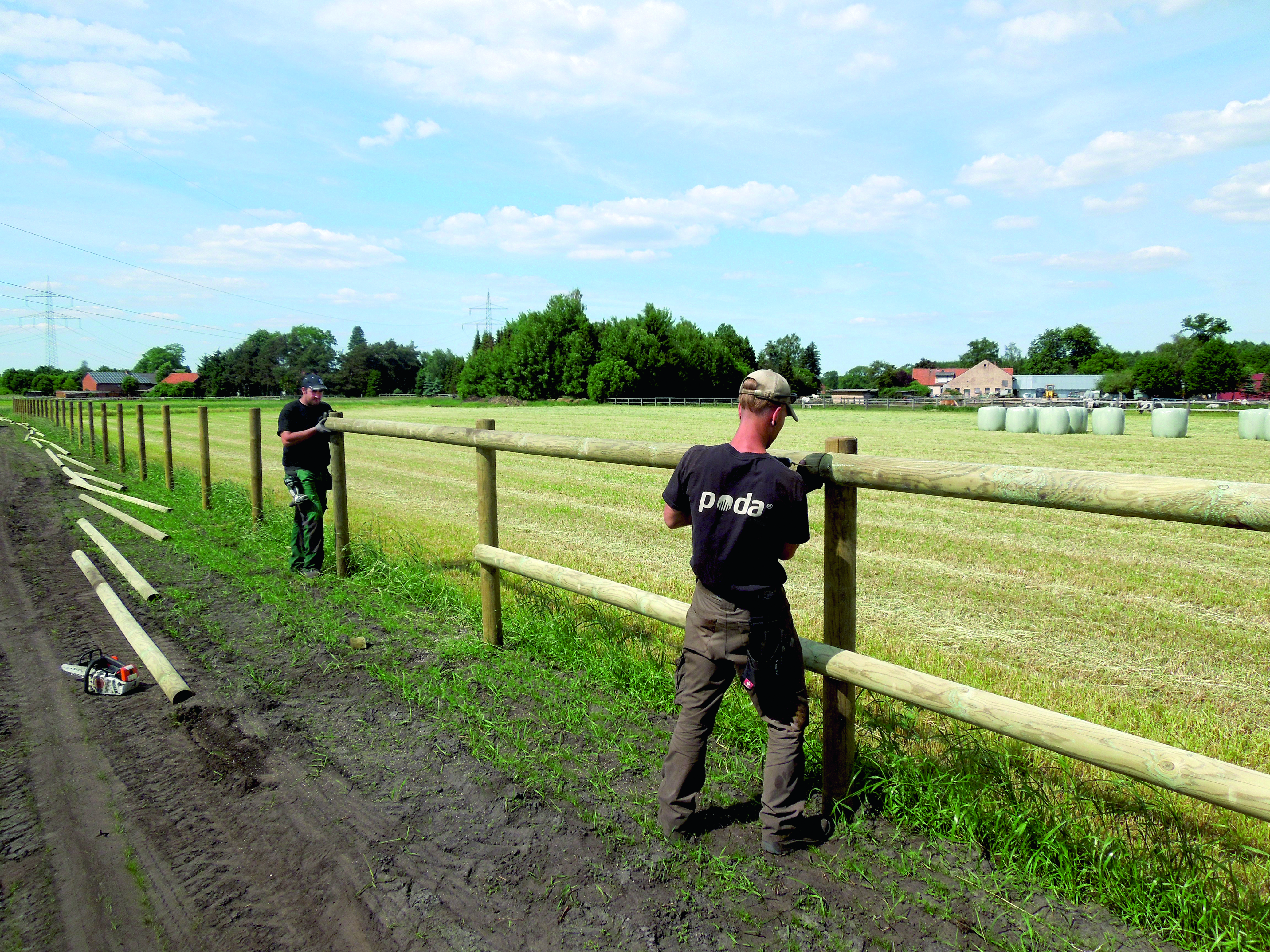 To montører fra Poda monterer et klassisk lektegjerde langs en jordvei.