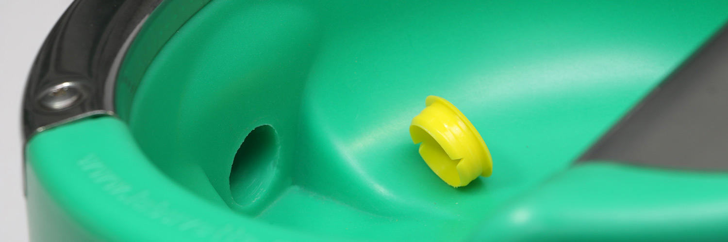 Nærbilde av en grønn drikkekopp med en gul plastpropp ved en åpning.