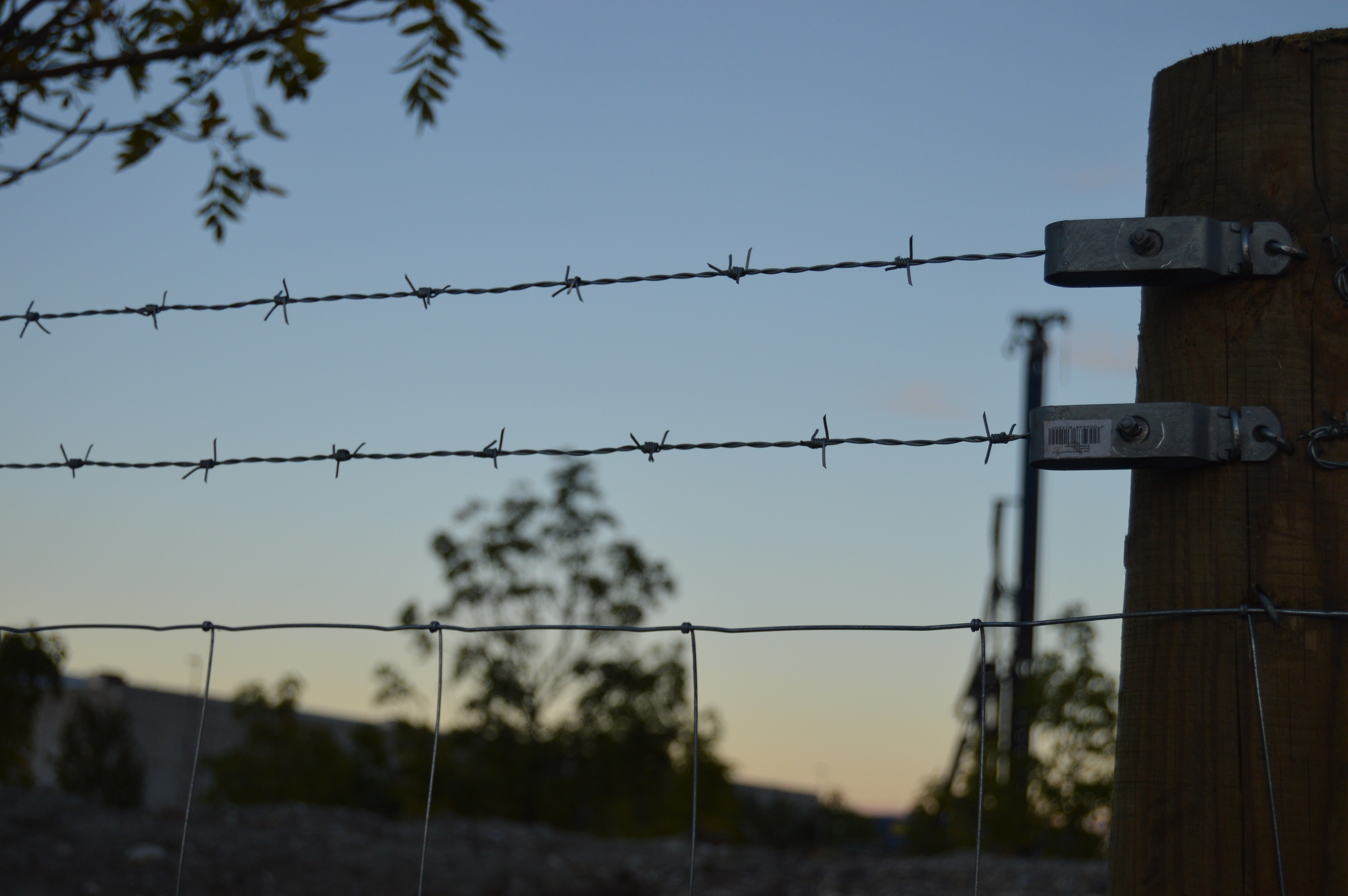 Nærbilde av piggtråd på toppen av et gjerde på en byggeplass